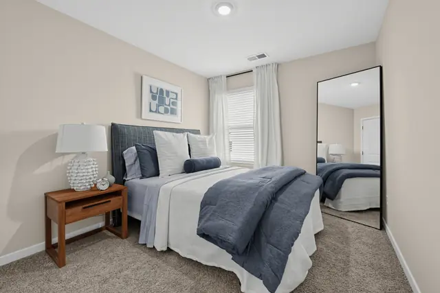 Maywood secondary bedroom with queen bed and full-length mirror