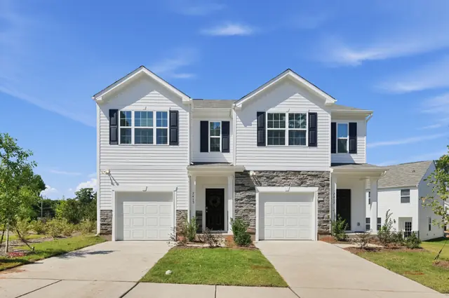 Pair of two-story Hubbard townhomes with white siding, stone accents, and attached garages