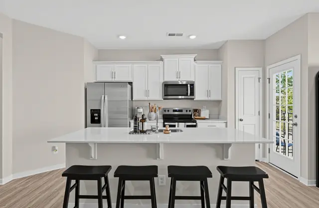 Maywood kitchen island with bar seating, white cabinets, and stainless appliances