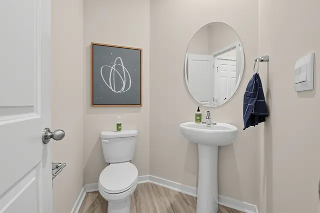 Maywood powder room with pedestal sink and round mirror