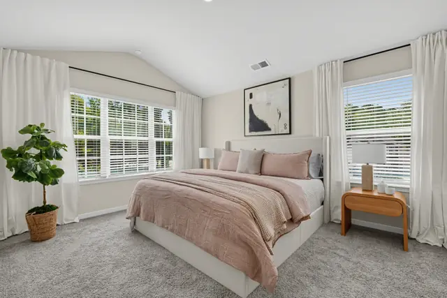 Maywood primary bedroom with vaulted ceiling and two windows